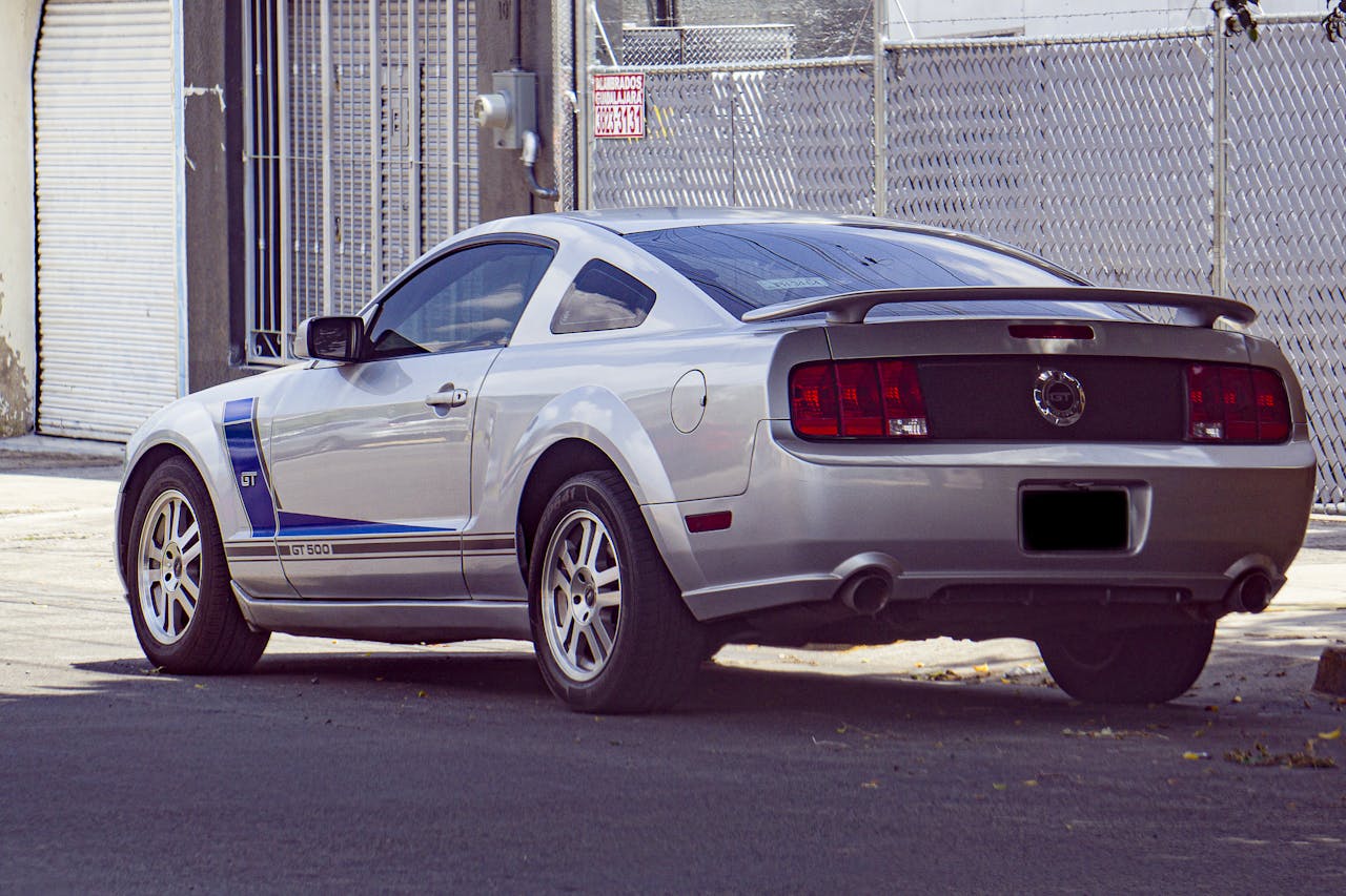 Sleek silver GT sports car parked on an urban street near a garage door.